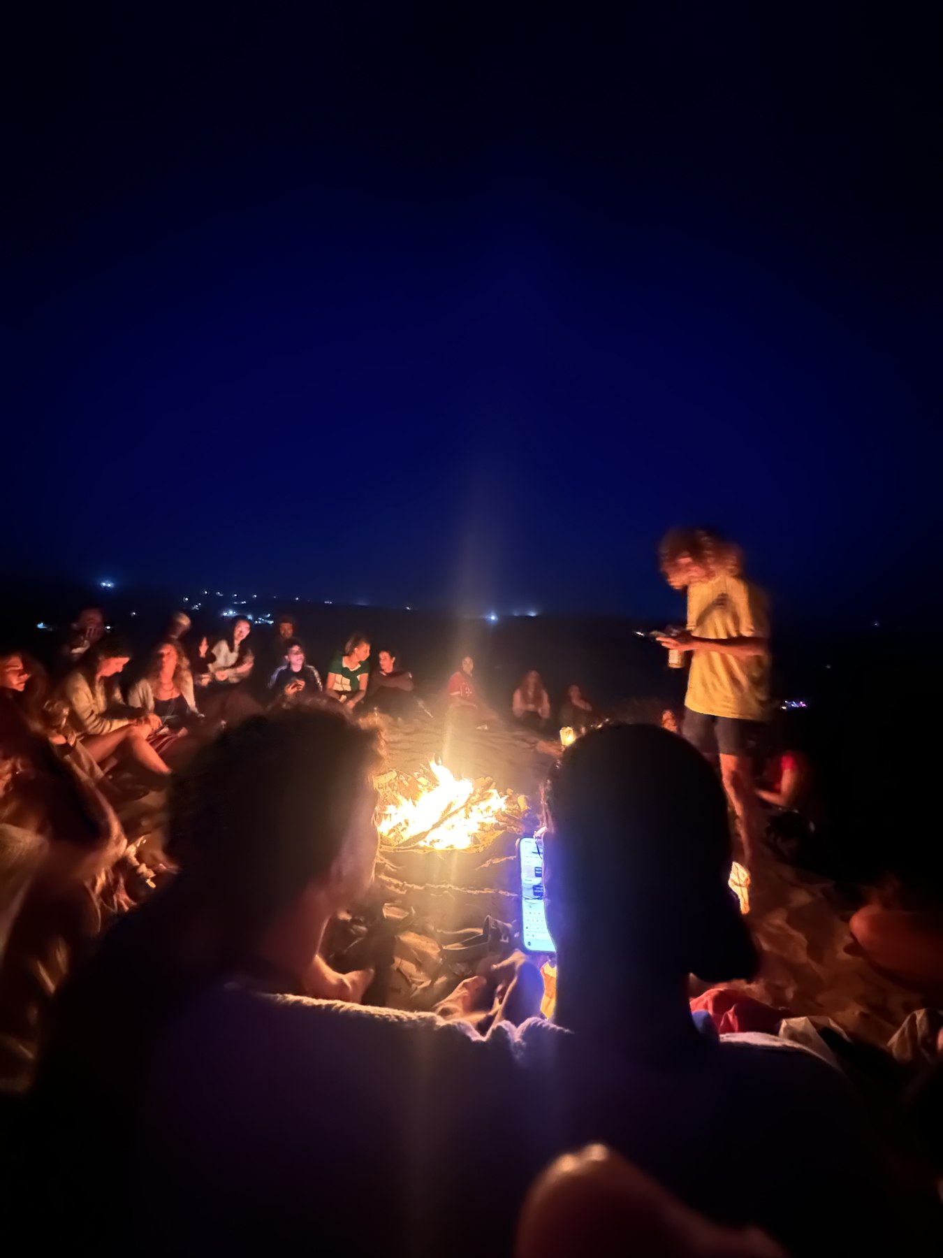 Friends gathered around a fire after dark