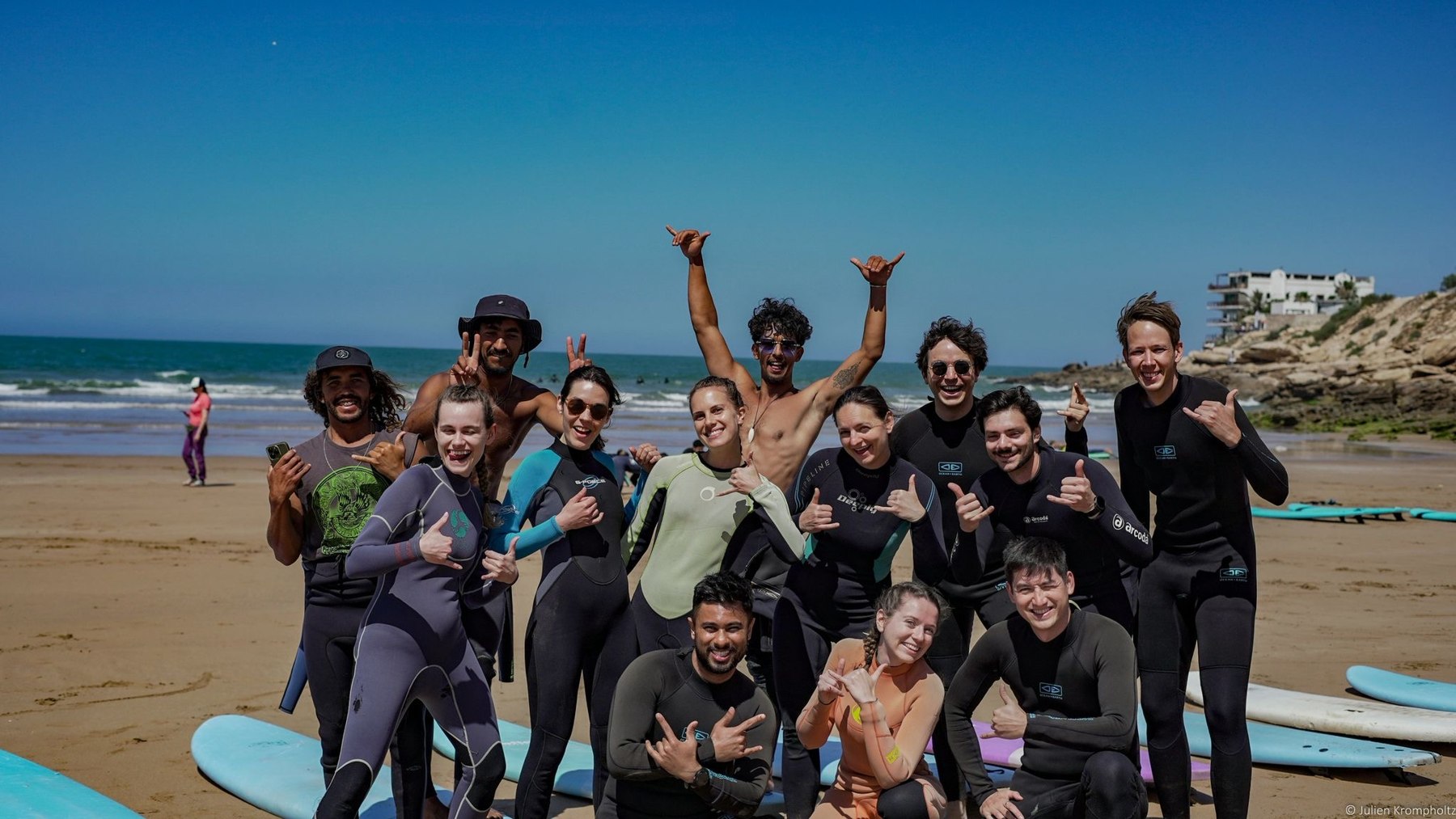 A group of surfers smiling together on the beach